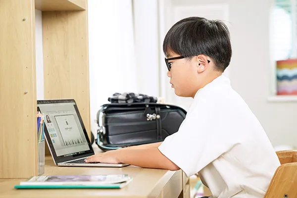自宅の学習机でオンラインレッスンを受ける男の子