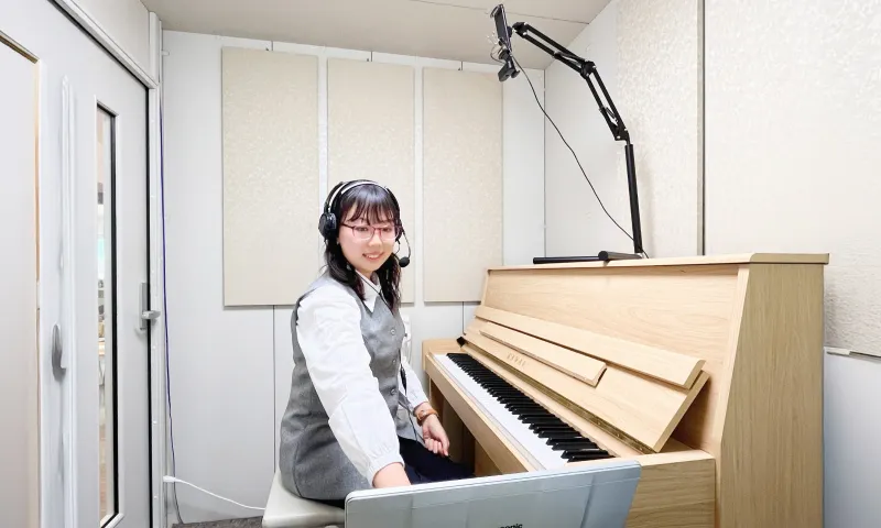 ピアノを前に座る講師とレッスン配信のための機材セット